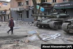 Жительница Мариуполя и военная техника так называемой "ДНР" на улице в Мариуполе. 4 мая 2022 года. Фото: AP